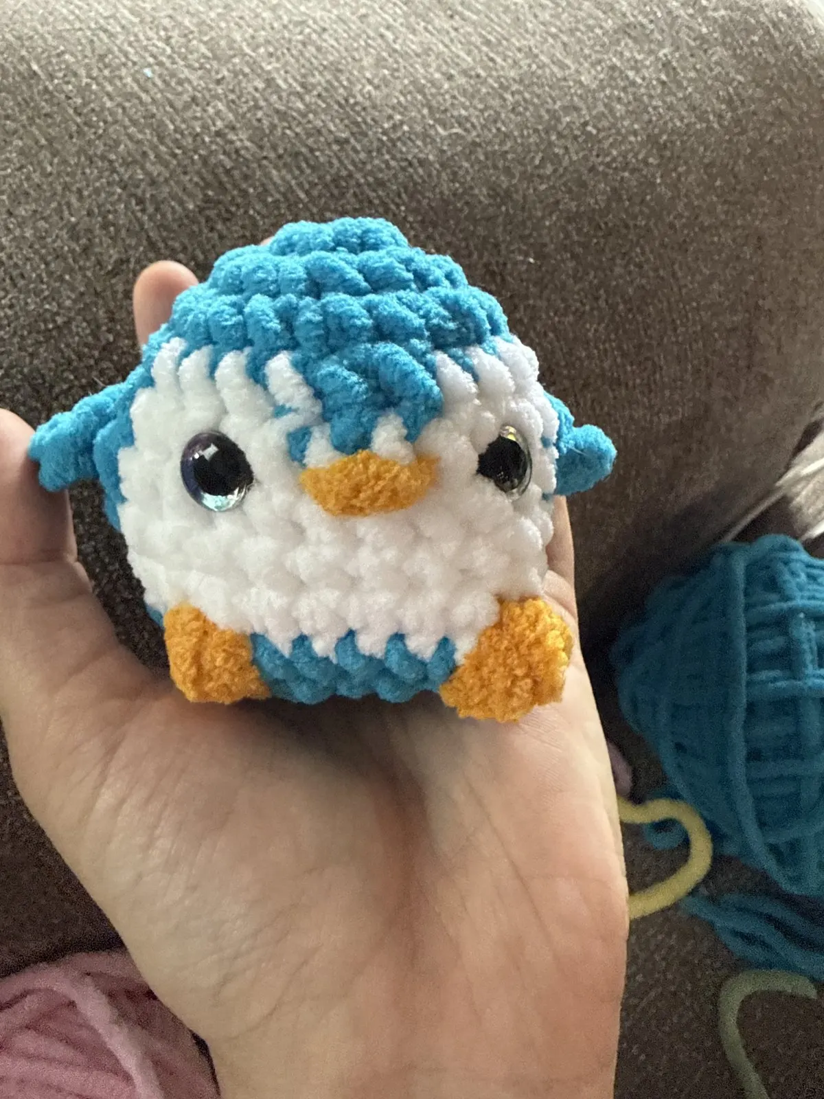 Small blue crochet penguin held in a hand