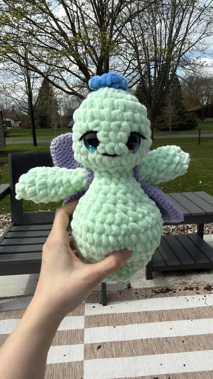 A mint crochet fairy plush held outdoors